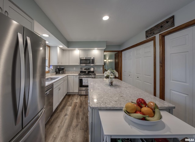 kitchen featuring a sink, stainless steel appliances, dark wood finished floors, a center island, and white cabinets