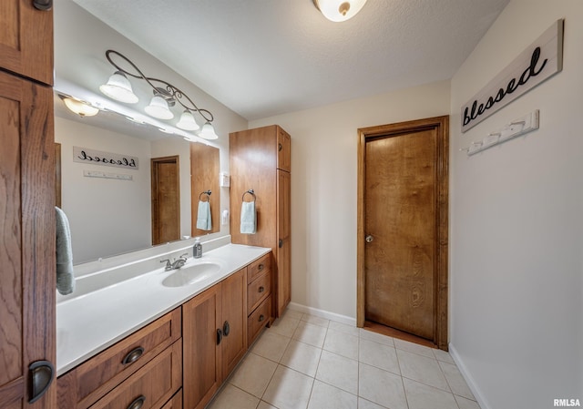 bathroom featuring a textured ceiling, baseboards, tile patterned flooring, and vanity