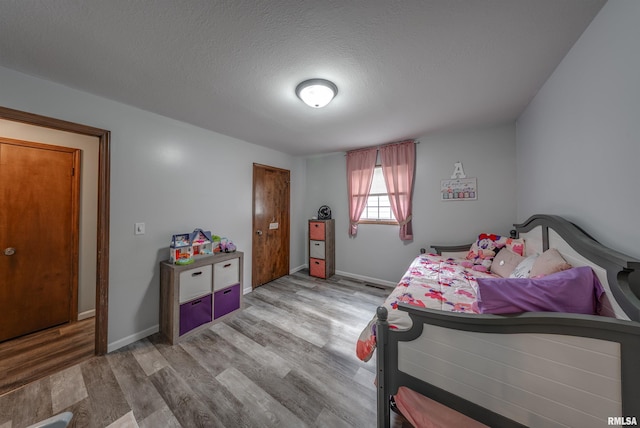 bedroom featuring a textured ceiling, wood finished floors, and baseboards
