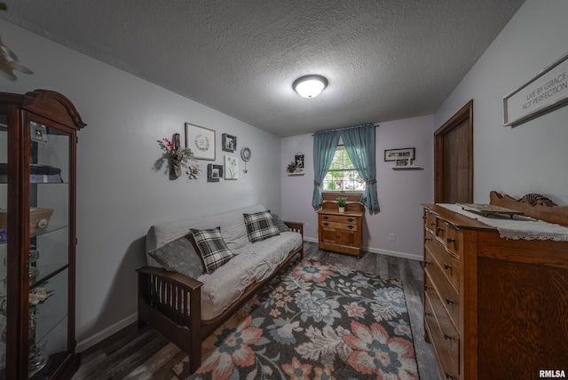 bedroom featuring a textured ceiling, dark wood-style flooring, and baseboards