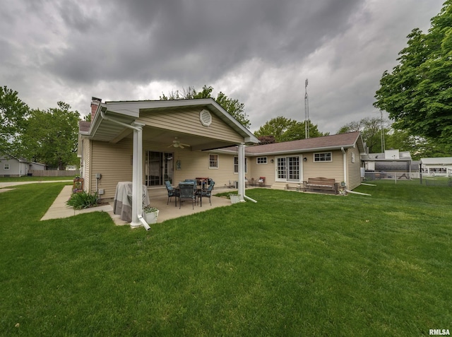 rear view of property featuring a ceiling fan, a chimney, a patio area, and a lawn