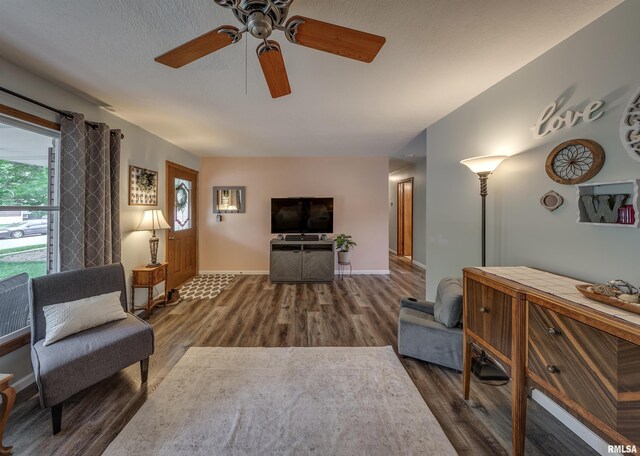 living room with wood finished floors, baseboards, and ceiling fan