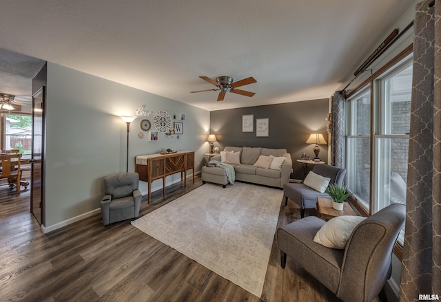 living area with baseboards, a ceiling fan, and wood finished floors