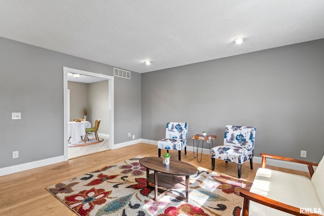 living area with wood finished floors, visible vents, and baseboards