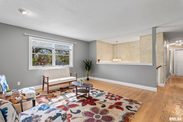 sitting room with baseboards, wood finished floors, and a textured ceiling