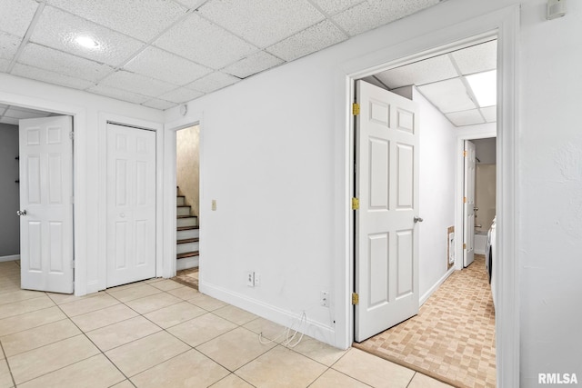 unfurnished bedroom with light tile patterned floors, a closet, a paneled ceiling, and baseboards