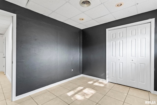 unfurnished bedroom featuring tile patterned flooring, a paneled ceiling, visible vents, and baseboards
