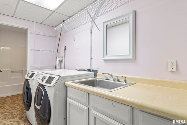 washroom with cabinet space, separate washer and dryer, and a sink