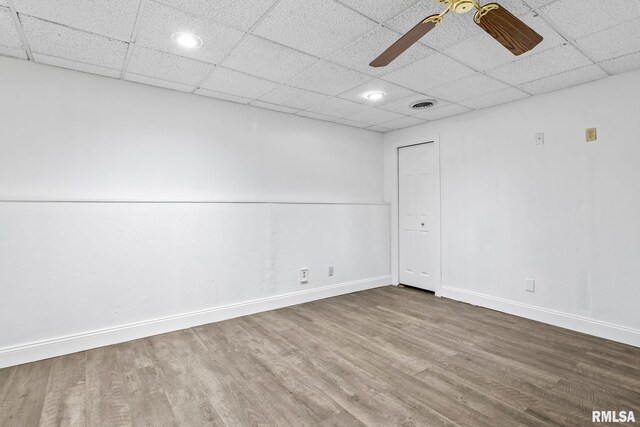 empty room with a ceiling fan, visible vents, wood finished floors, and baseboards