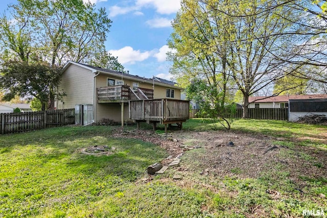 rear view of property featuring a lawn, a deck, and a fenced backyard