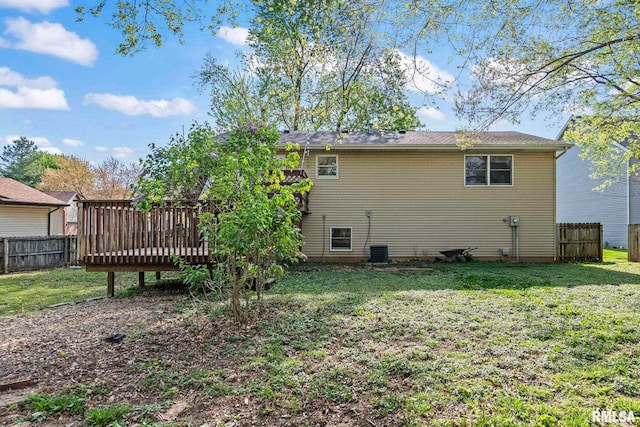 back of property with a deck, a yard, central AC unit, and fence