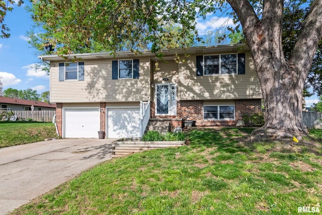 split foyer home featuring brick siding, a front yard, and fence