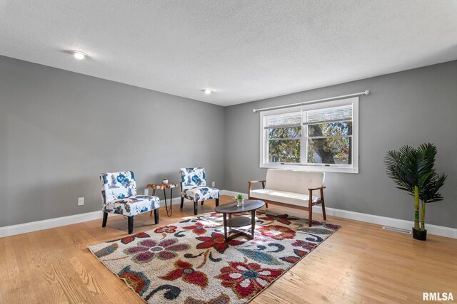 sitting room with baseboards, wood finished floors, and a textured ceiling