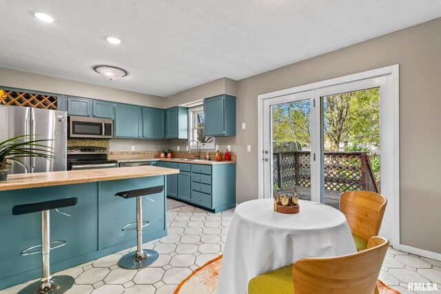 kitchen featuring a sink, blue cabinetry, stainless steel appliances, and light countertops