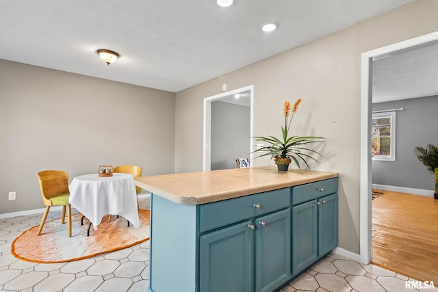 kitchen featuring recessed lighting, blue cabinetry, light countertops, baseboards, and a textured ceiling