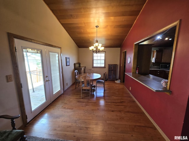 dining room with a chandelier, wood finished floors, french doors, and vaulted ceiling