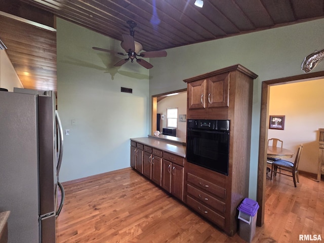 kitchen featuring light wood-style floors, a ceiling fan, visible vents, black oven, and freestanding refrigerator