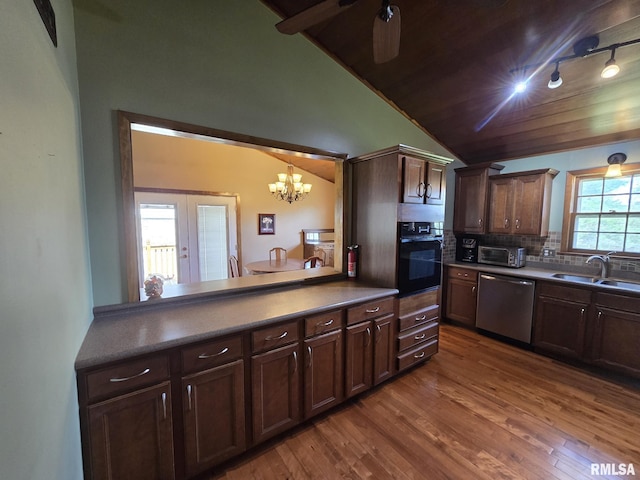kitchen with track lighting, stainless steel dishwasher, black oven, a sink, and dark wood-style floors