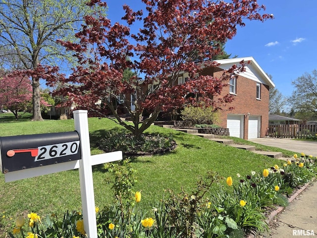 view of front of home featuring concrete driveway, a front yard, brick siding, and a garage