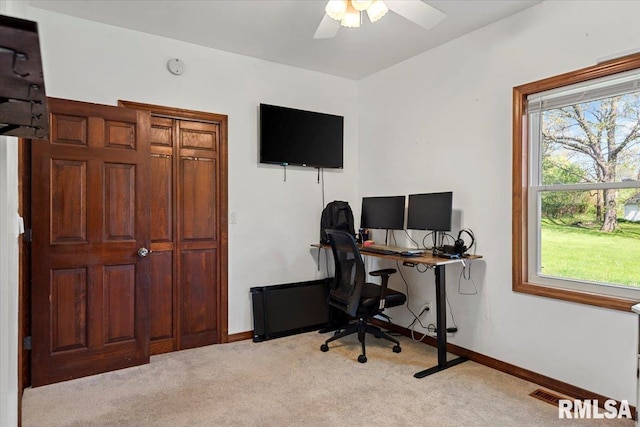 office space with baseboards, a ceiling fan, and light carpet