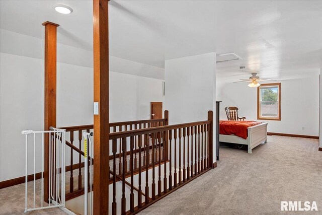 corridor with carpet floors, baseboards, and an upstairs landing