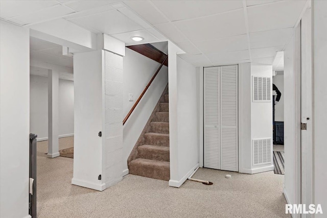 finished basement featuring a paneled ceiling, carpet, stairs, baseboards, and visible vents