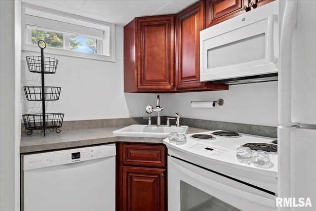 kitchen with a sink, dark countertops, dark brown cabinets, and white appliances