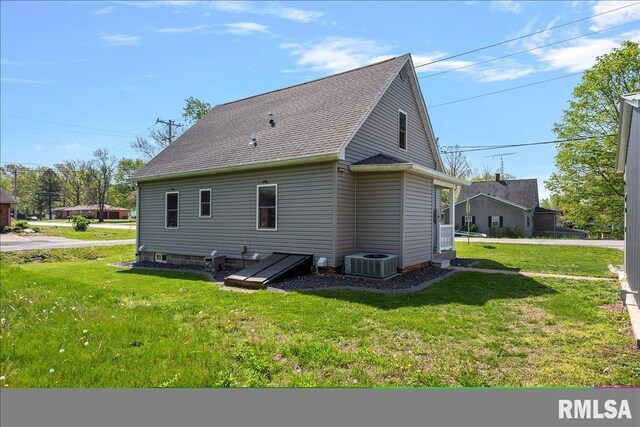 back of property with a lawn, roof with shingles, and central AC