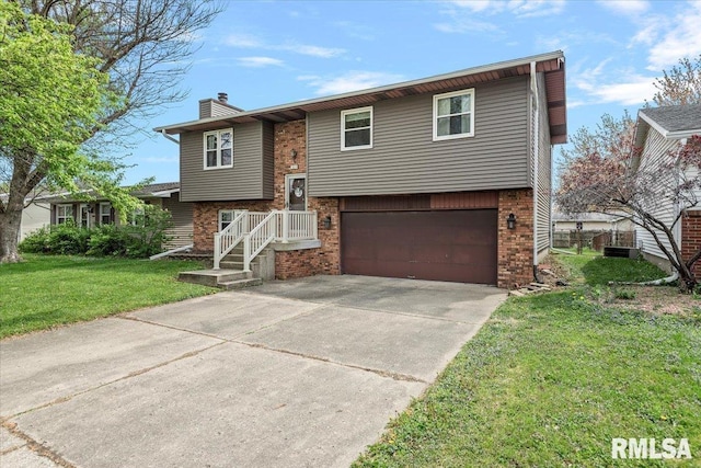 split foyer home featuring driveway, a chimney, a front lawn, brick siding, and a garage