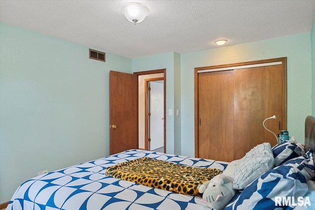 bedroom with a textured ceiling, visible vents, and a closet
