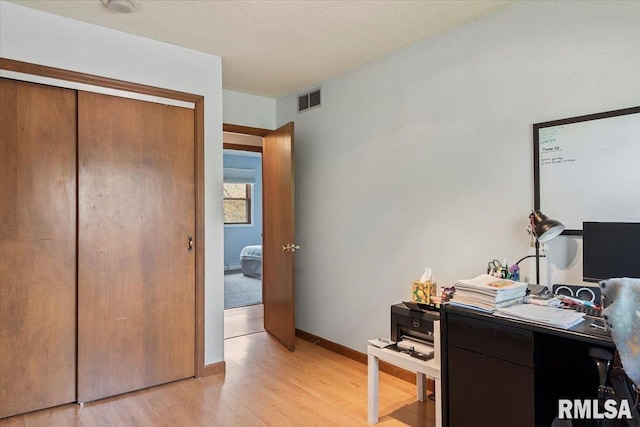 office with baseboards, visible vents, and light wood-type flooring