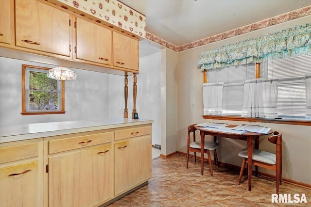 kitchen with light brown cabinetry, baseboards, a notable chandelier, and light countertops