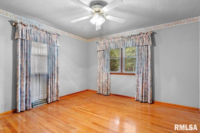 empty room with a ceiling fan, baseboards, visible vents, and wood finished floors