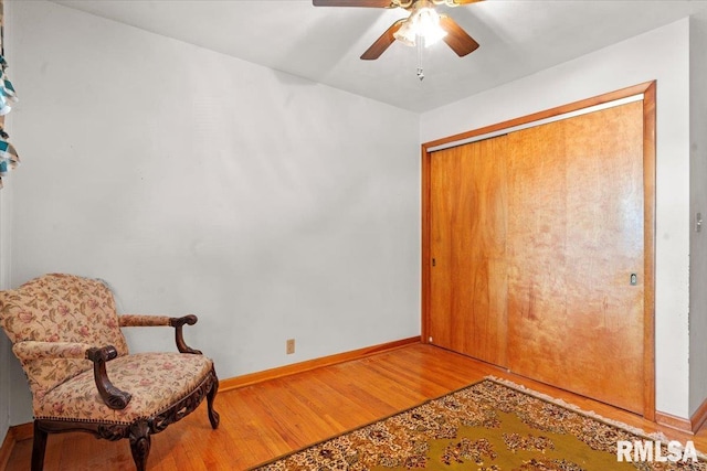 sitting room featuring baseboards, a ceiling fan, and light wood-type flooring