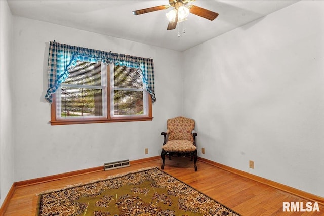 sitting room with baseboards, ceiling fan, wood finished floors, and visible vents
