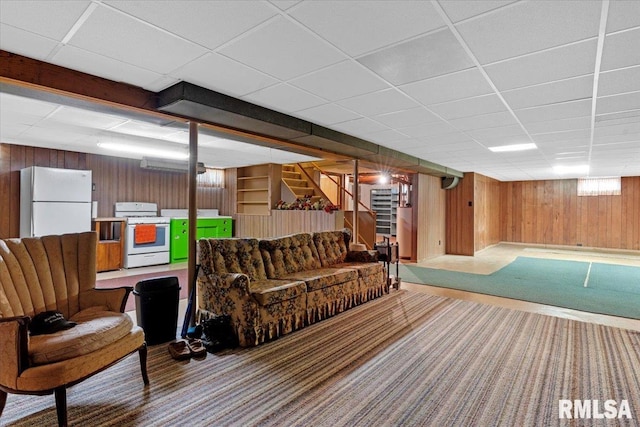 interior space with wooden walls, a drop ceiling, stairs, and carpet