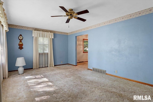 carpeted spare room with baseboards, a wealth of natural light, and visible vents