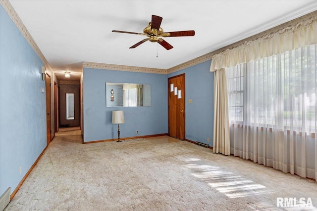 interior space featuring crown molding, carpet floors, baseboards, and a ceiling fan