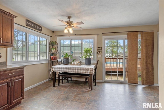 dining space featuring a textured ceiling, a ceiling fan, and baseboards