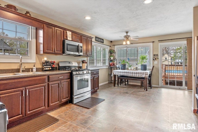 kitchen featuring appliances with stainless steel finishes, plenty of natural light, baseboards, and a sink