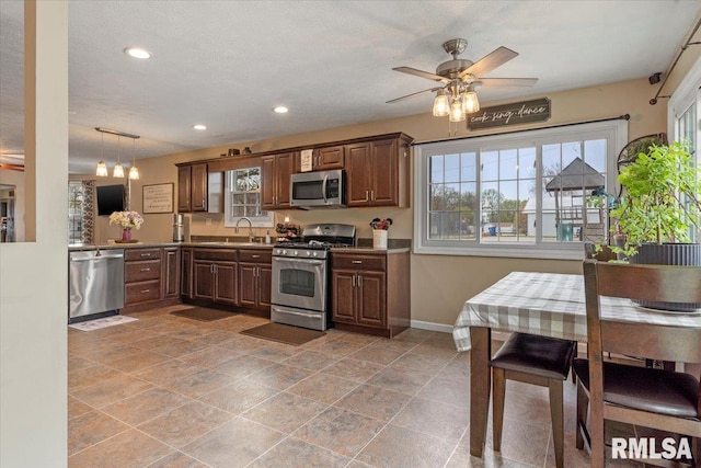 kitchen featuring a wealth of natural light, stainless steel appliances, a ceiling fan, and baseboards