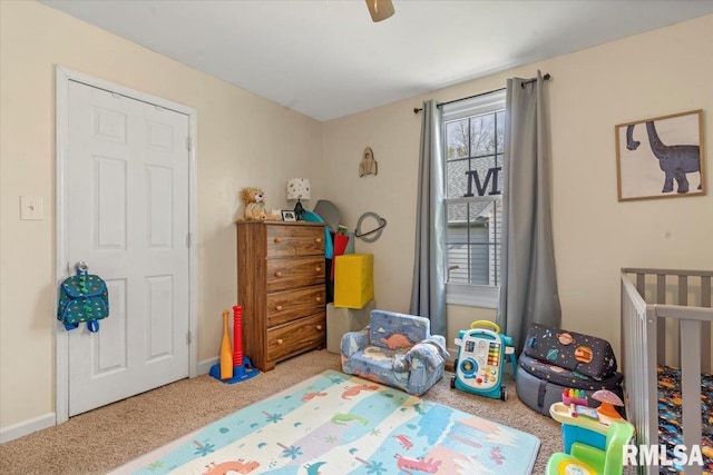bedroom with a crib, ceiling fan, and carpet