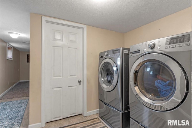 laundry room with washing machine and dryer, a textured ceiling, laundry area, and baseboards
