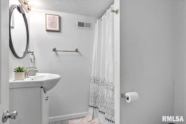 bathroom featuring visible vents, a textured ceiling, curtained shower, and vanity