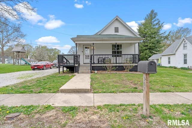 view of front of property featuring driveway, a porch, a front lawn, and a playground