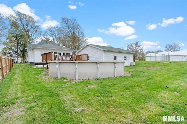 rear view of house featuring a deck, fence, a swimming pool, and a lawn