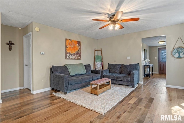 living room featuring baseboards, attic access, ceiling fan, and wood finished floors