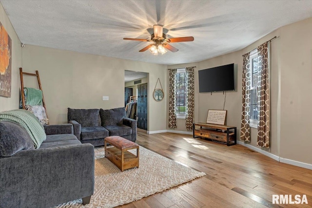 living area featuring a textured ceiling, hardwood / wood-style floors, ceiling fan, and baseboards