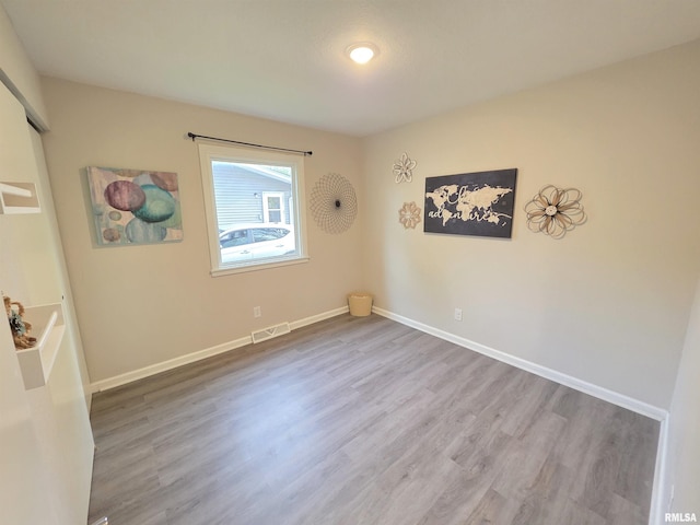 unfurnished room featuring baseboards, visible vents, and wood finished floors