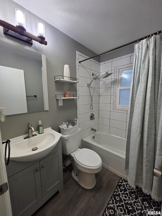 bathroom featuring wood finished floors, shower / bath combination with curtain, toilet, vanity, and a textured ceiling